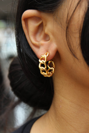 Close-up of a model wearing a Tied in Gold Hoop Earrings with a blurred background