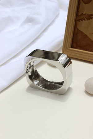 Lucid Hour Bracelet on a white surface with a wooden frame in the background