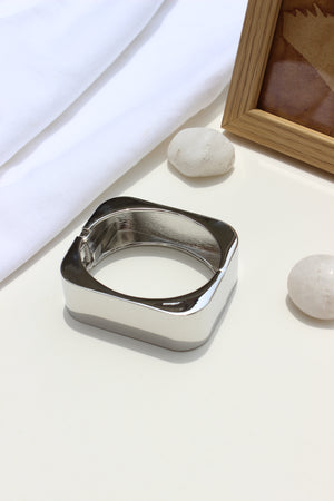 Lucid Hour Bracelet on a white surface with a wooden frame and stones in the background