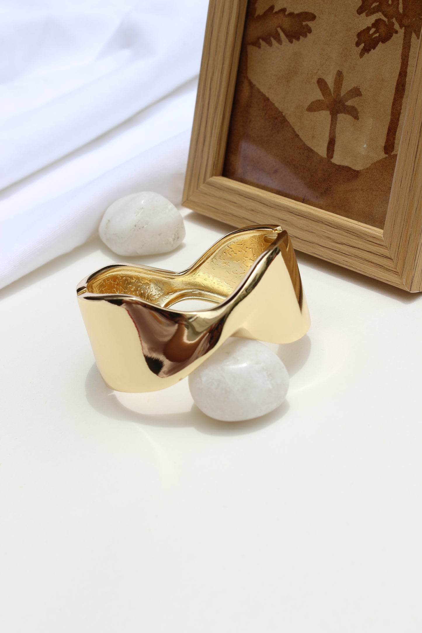 Molten Curve Bracelet on a white surface with a wooden frame in the background