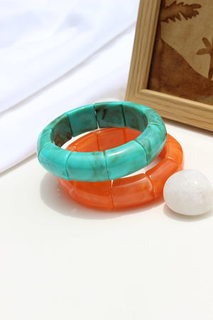 Peach Orbit Bangle Bracelets on a white surface with a blurred background