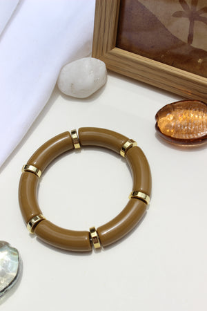 Mocha Toffee Bangle Bracelet on a white surface with decorative stones and wooden frame