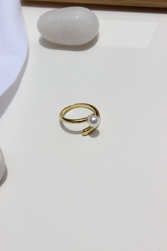 Folded Glow Ring with a pearl on a white surface