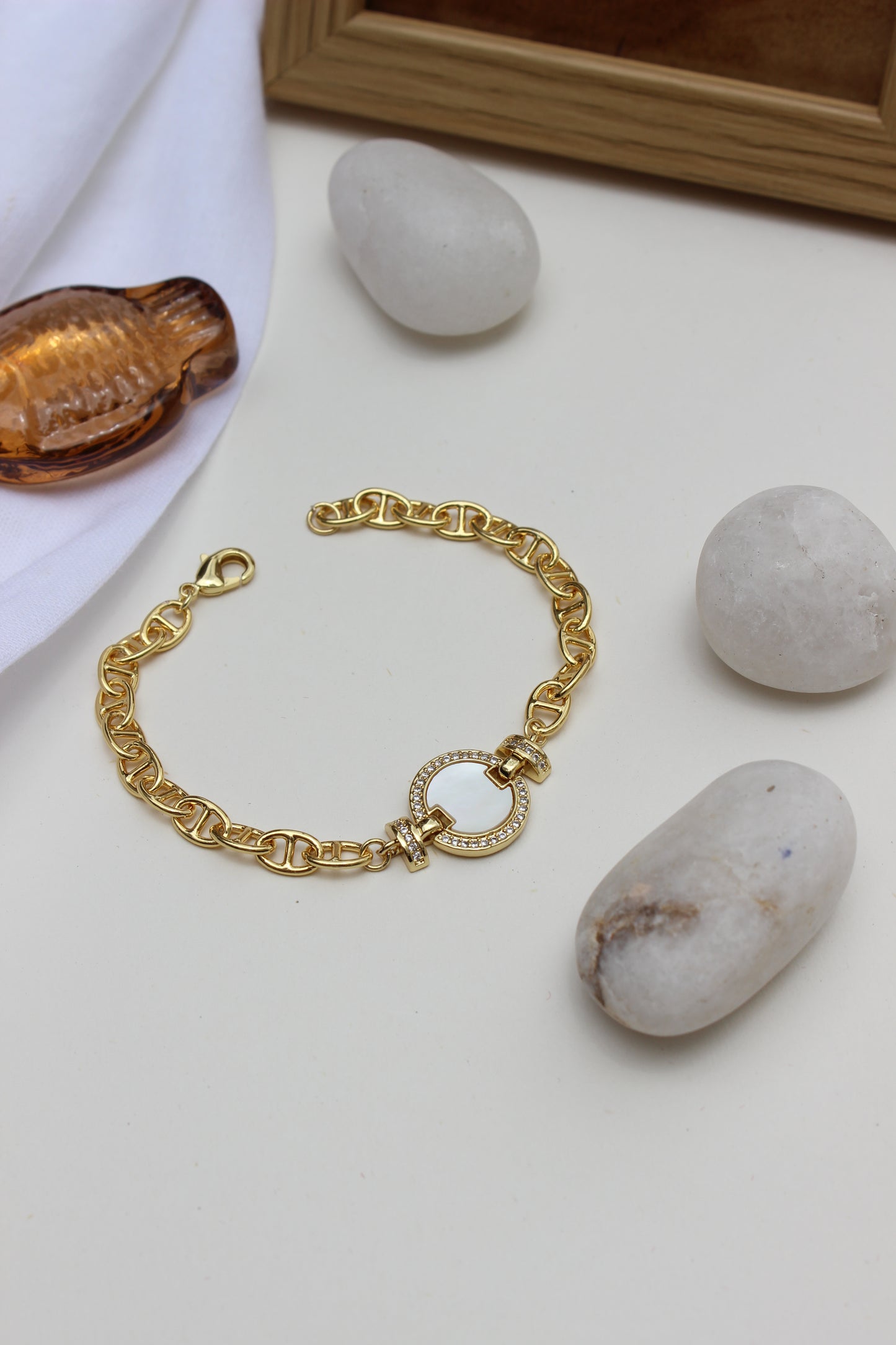 Sea of Light Bracelet on a light surface with stones and a wooden frame in the background