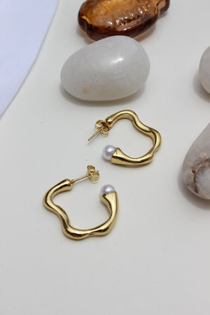 Pearl Fold Half Hoop Earrings on a light surface with stones