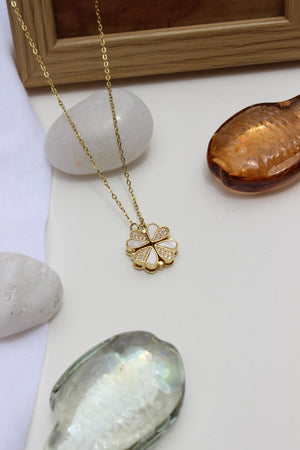 Oyster Petal Pendant Necklace on a white surface with seashells and a wooden frame