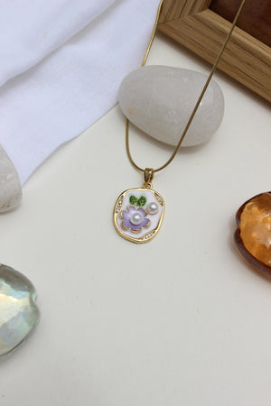 Gold chain with enamel flower pendant displayed on minimal flat lay with gemstones