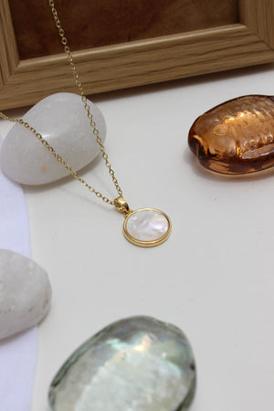 Melted Calm Pendant Necklace on a white surface with stones and a frame