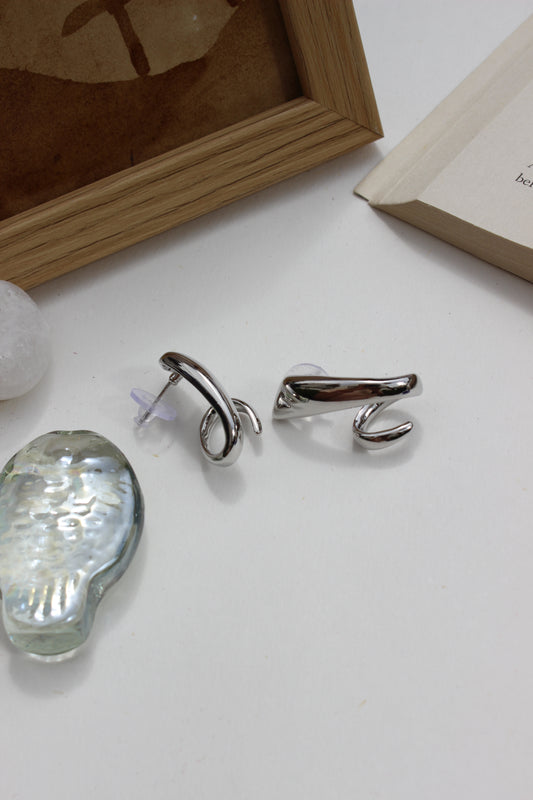 Midnight Curve Earrings on a white surface with a wooden frame in the background