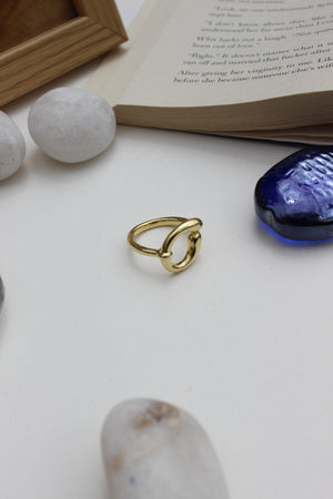 Warm Loop Ring on a white surface with book and stones
