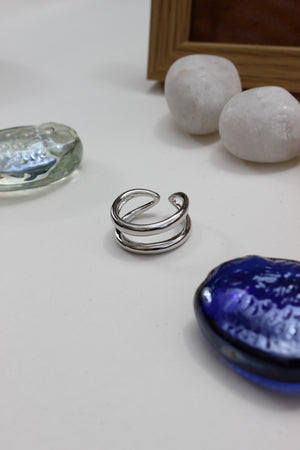 Brushed Moon Ring on a white surface with decorative stones and a blue seashell