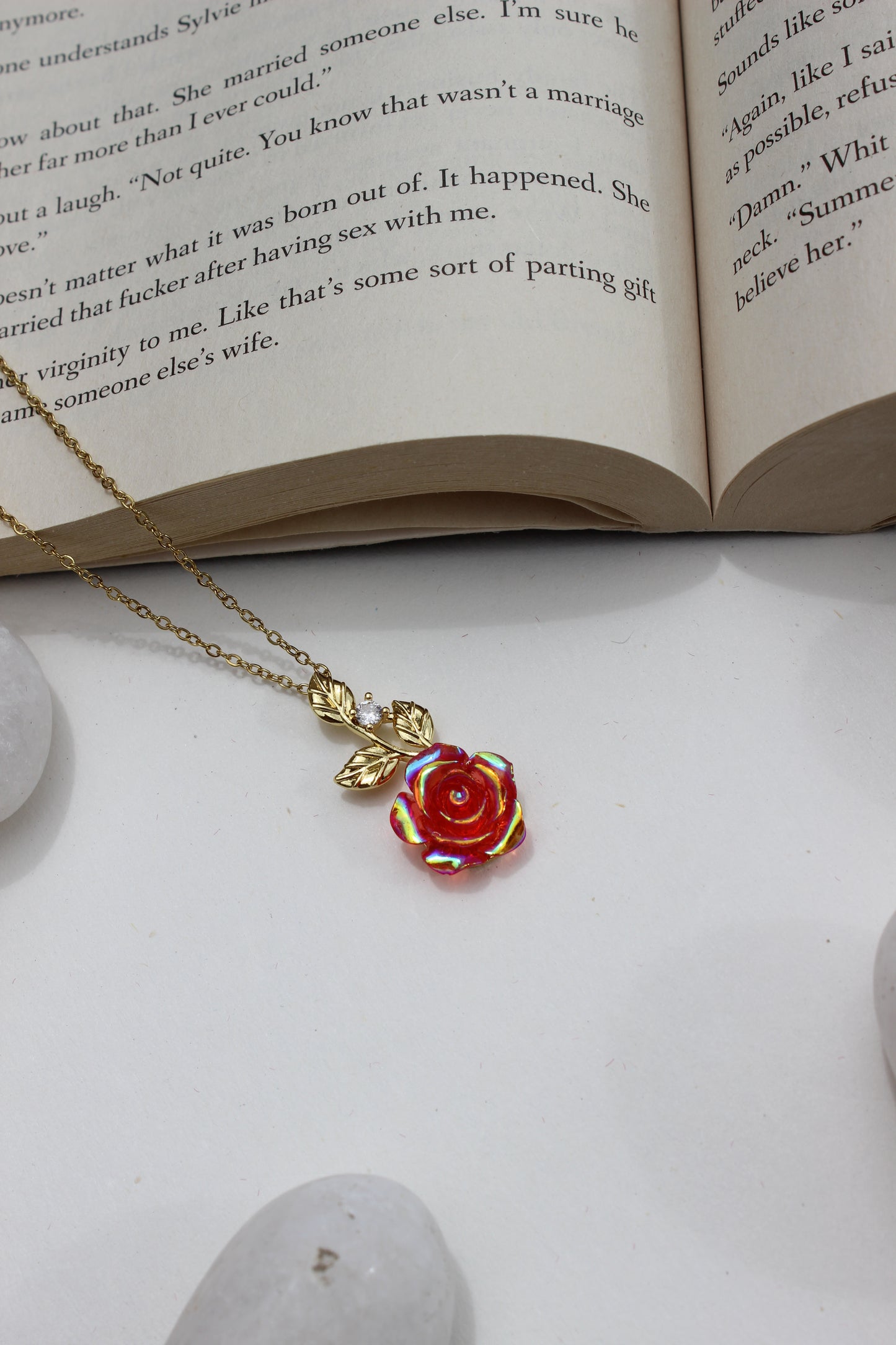 Primrose Dawn Pendant Necklace on an open book with a stone surface underneath