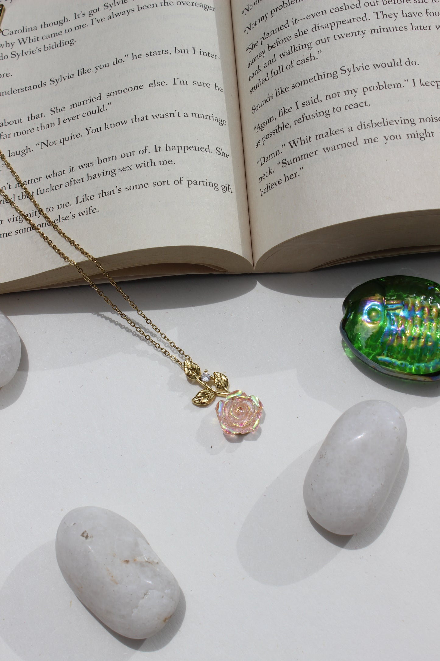 Primrose Pendant Necklace on an open book next to pebbles