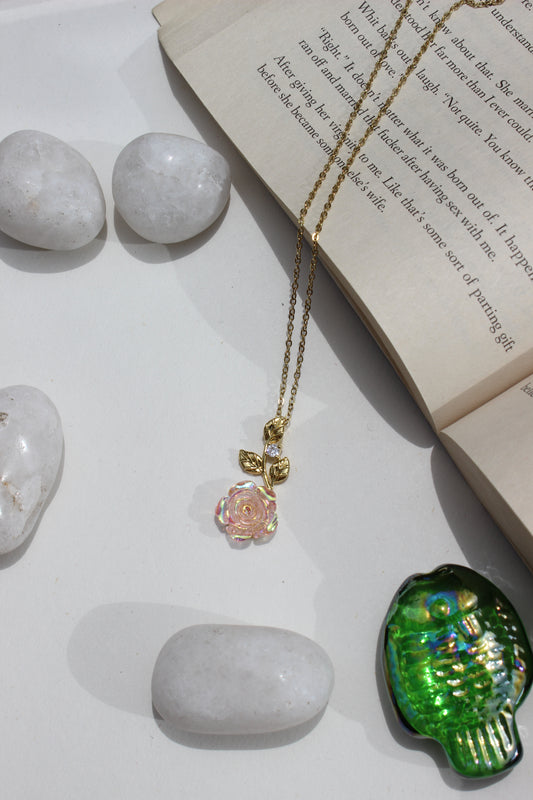 Primrose Pendant Necklace on a white surface next to an open book