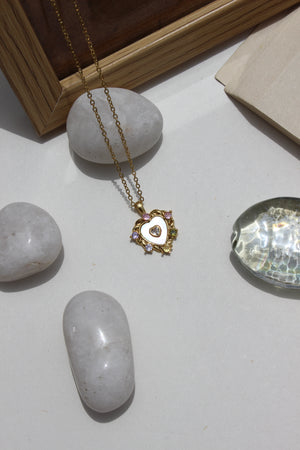 Everglow Heart Pendant Necklace on a white surface with rocks