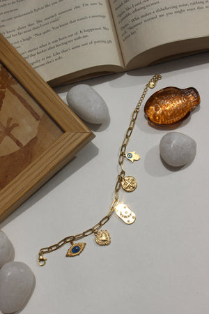 Whispershield Charms Bracelet with decorative elements on a surface with stones and an open book