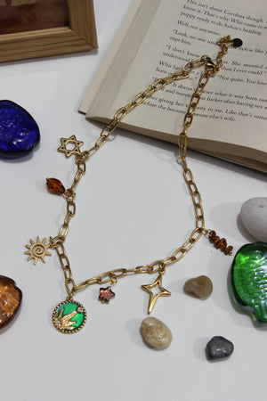 Amberjoy Charms Necklace on a white surface with a book and stones