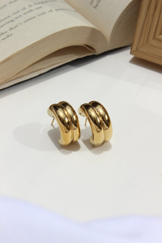 Soline Earrings on a white surface with an open book in the background