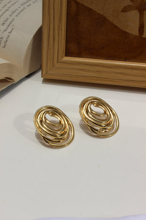 Gleamette Earrings on a white surface with a wooden frame and book in the background