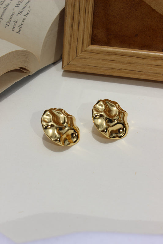 Musecore Stud Earrings on a white surface with a wooden frame in the background
