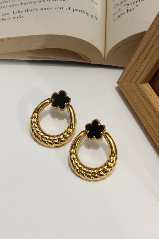 Orbella Earrings on a white surface next to an open book