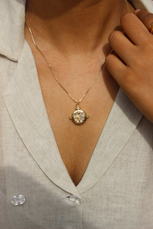 Close-up of a Whitespell Pendant Necklace on a person wearing a beige jacket