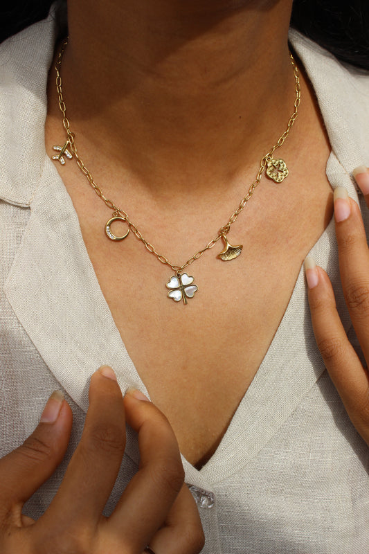 Where She Wanders Charm Necklace with floral and moon designs on a person's ankle against a neutral background