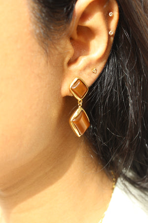 Amber Dust Earrings on an ear with a blurred background