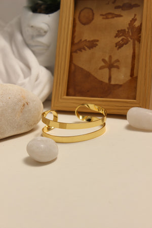 Monarch Cuff Bracelet on a hook with a wooden frame and pebbles in the background