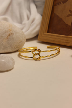 Eterna Knot Cuff Bracelet on a stone surface with a soft background