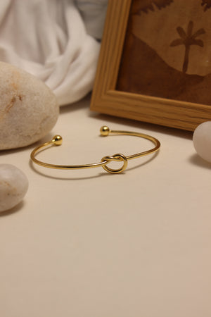 Entwine Cuff Bracelet on a neutral background with stones and a wooden frame