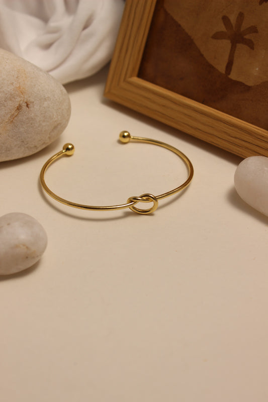 Entwine Cuff Bracelet on a beige surface with stones and a wooden box