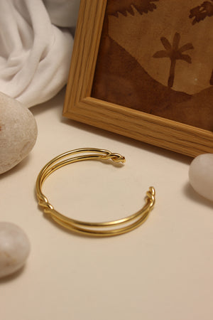 Nexus Cuff Bracelet on a neutral background with a wooden frame and fabric