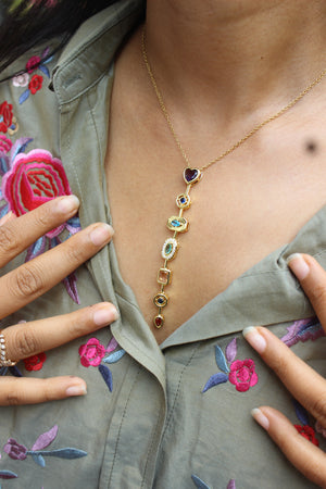 Amour Pour Necklace with heart and flower charms on a model's neck, wearing a green embroidered jacket