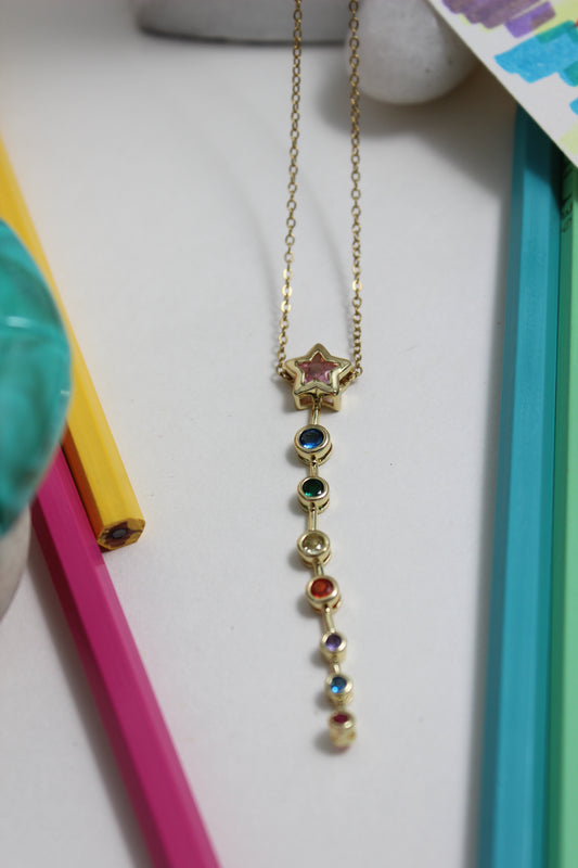 Nova Drip Necklace with colorful stones on a white surface with colorful objects around
