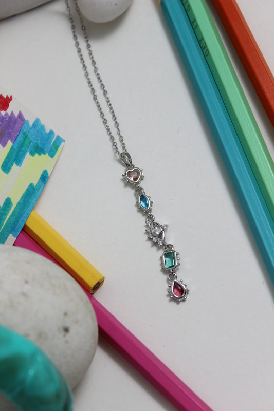Moonlit Fortuna Necklace with colorful gemstones on a white surface with colorful pencils