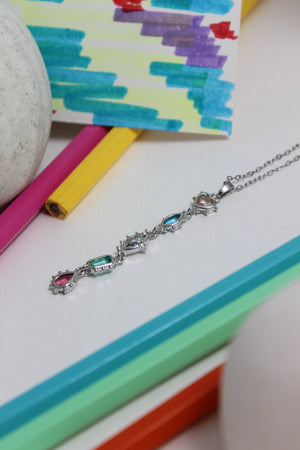 Moonlit Fortuna Necklace with colorful pendant on a colorful geometric background