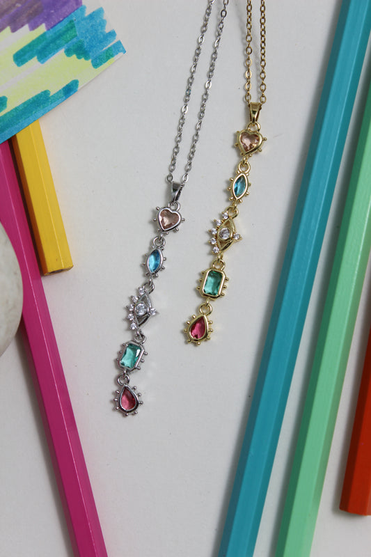 Moonlit Fortuna Necklace with colorful gemstones on a white background with colorful pencils