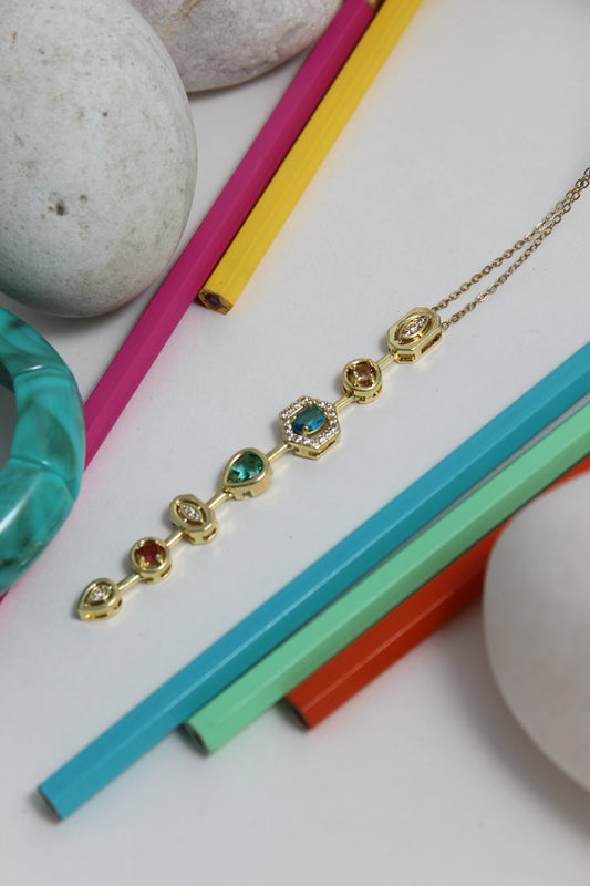 Stellar Pour Necklace with colorful beads on a white surface with colorful pencils and stones