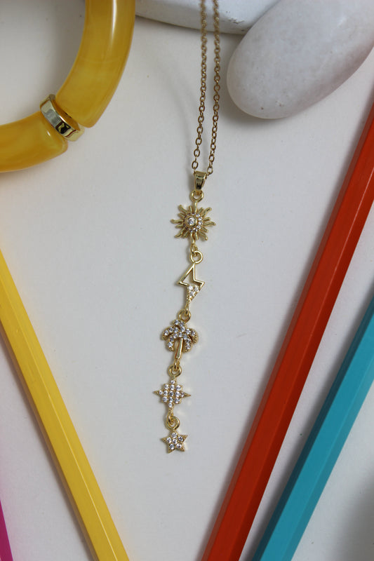 Golden Palm Necklace with star designs on a white surface with colorful pencils and stone