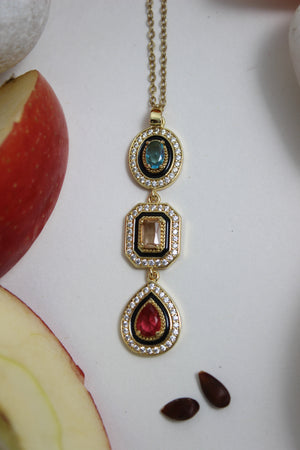 Noir Royale Necklace with gemstones on a white surface with apples and seeds