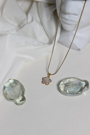 Gold Moonflower Pendant Necklace with a pendant on a white fabric background