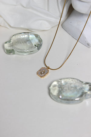 Oro Emeraude Glow Pendant Necklace with green gemstones and a gold pendant on a white background