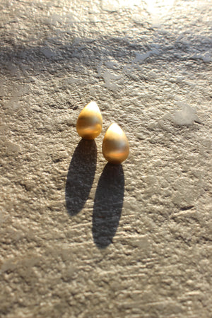 Gilded Weave Hoop Earrings on a textured stone surface