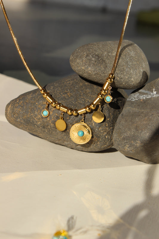 Solstice Medallion Necklace with turquoise stones on a stone surface