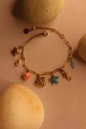 Oricca Charms Bracelet on a pink surface with stones