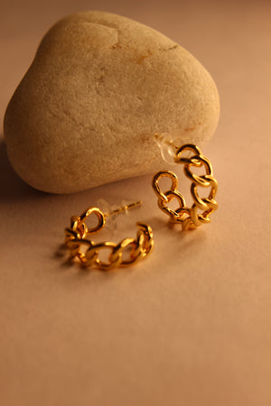 Tied in Gold Hoop Earrings on a stone surface with a warm brown background