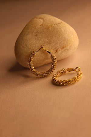 Lumira Hoop Earrings on a stone surface with a warm brown background