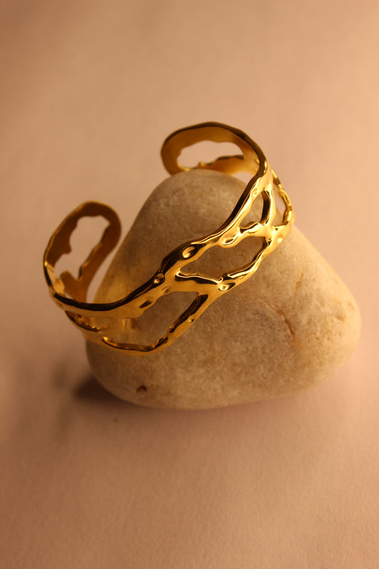 Orra Cuff Bracelet on a stone with a beige background