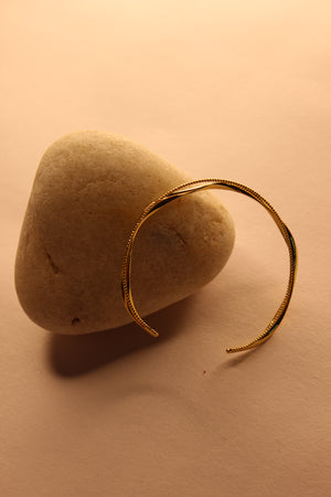 Auriin Cuff Bracelet on a beige stone against a beige background